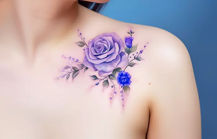 A soft watercolor purple and blue rose tattoo done on the collarbone