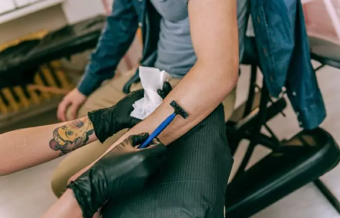 A tattoo artist shaving the area before the tattooing process