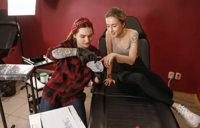 A tattoo artist showing a design to the client