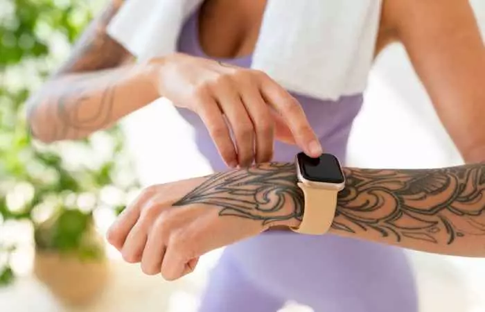 A tattooed woman checking her smartwatch after a workout session