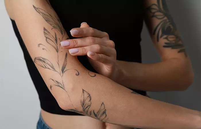 A woman applying aloe vera gel on her tattoo.