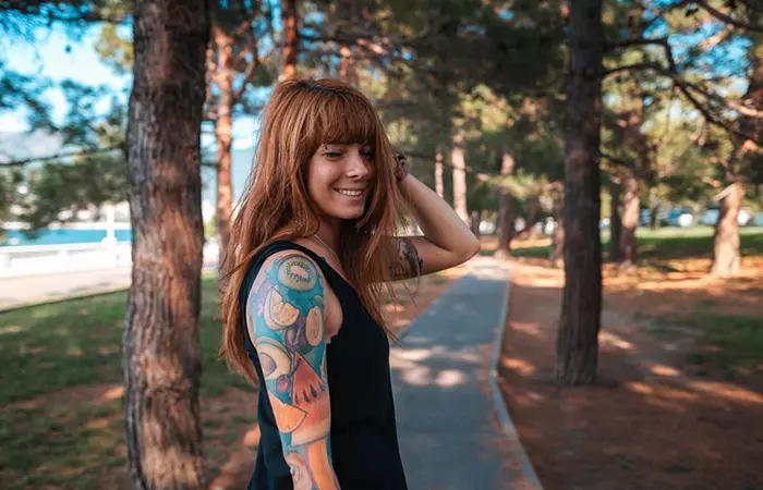A woman feeling happy and satisfied with her colorful sleeve tattoo