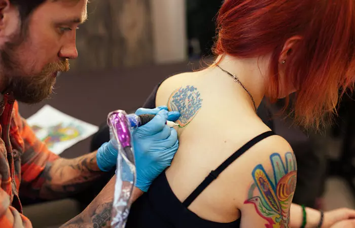 A woman getting tattooed by an expert tattooist