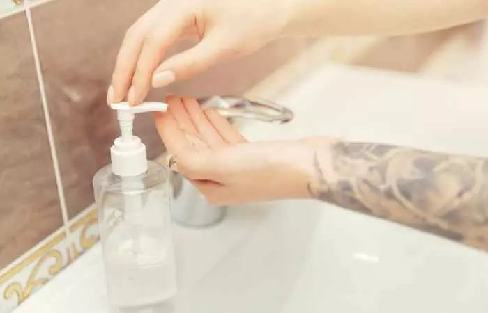 A woman using hand soap to wash her tattoo