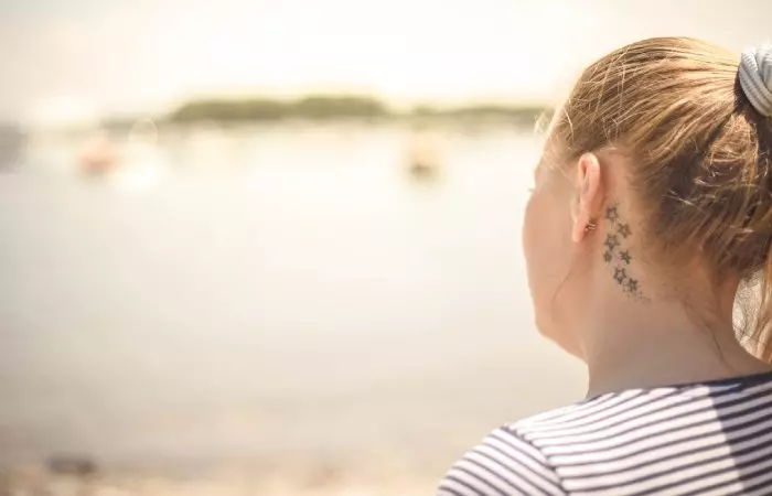 A woman with a behind-the-ear tattoo