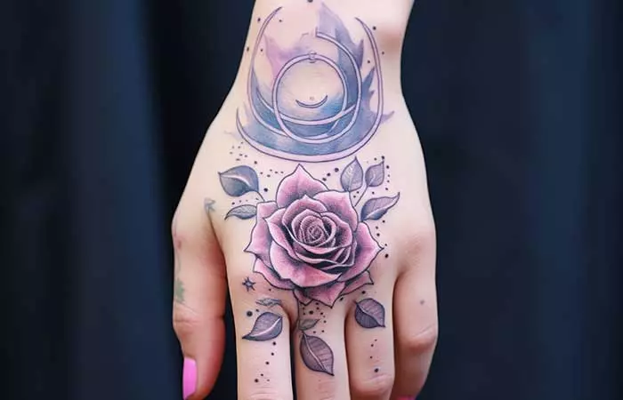 An abstract watercolor hand tattoo of a rose and moon phases
