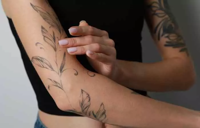 An individual applies moisturizer to ensure proper aftercare of their new tattoo.