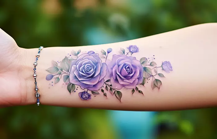 An ink-washed purple rose tattoo on the forearm