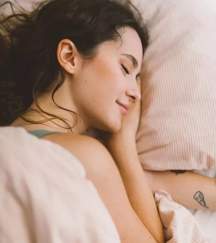 Woman with a tattoo on her sleeping on bed.