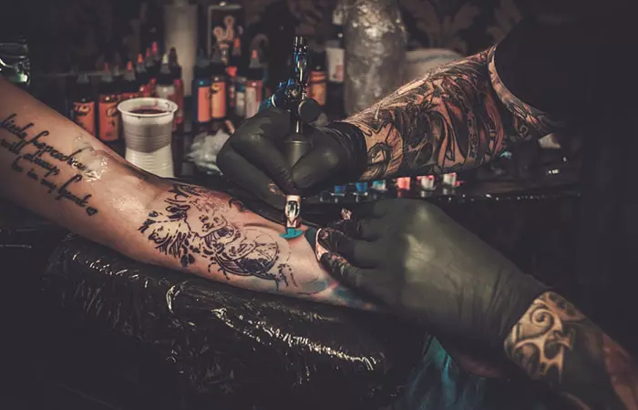A professional tattoo artist makes a tattoo on a young girl's hand