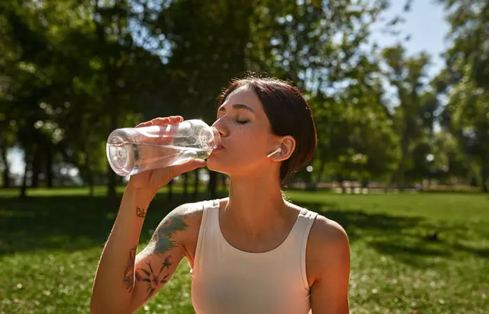 A tattooed woman drinking water