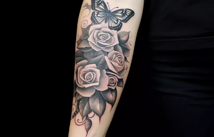 Black rose tattoo with butterfly on forearm