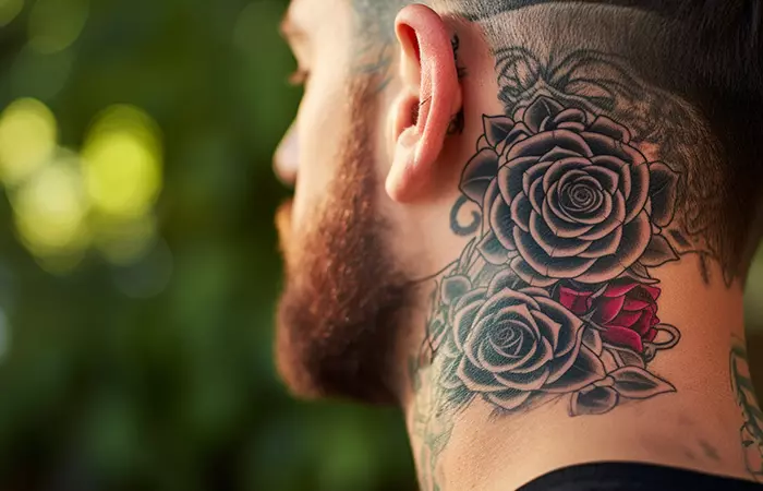 A blackwork rose neck tattoo behind the ear