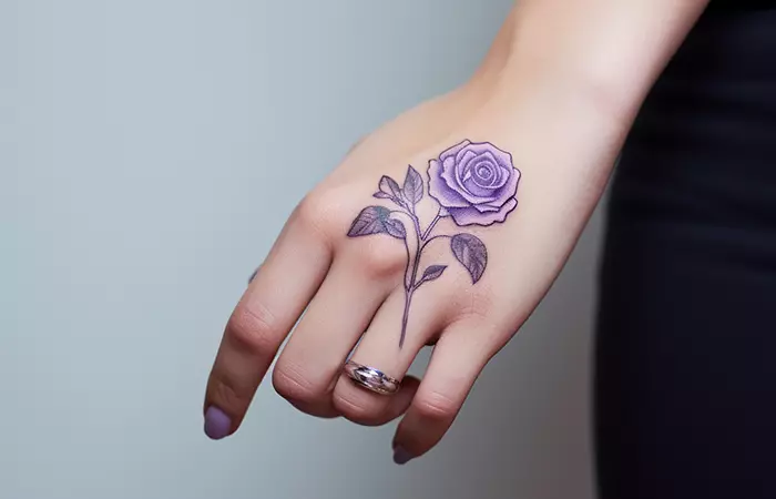 Minimalist purple rose tattoo on the back of the hand