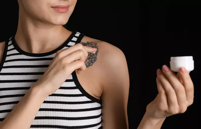 Woman applying moisturizer on raised tattoo