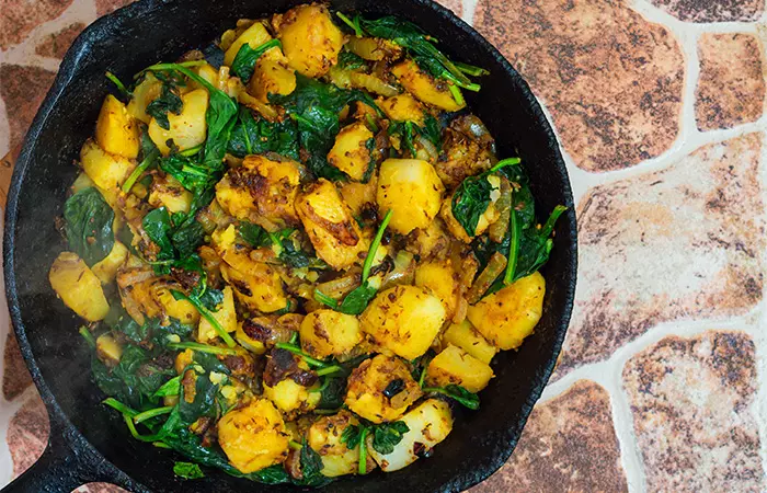 Potato and spinach curry in a cast iron pan