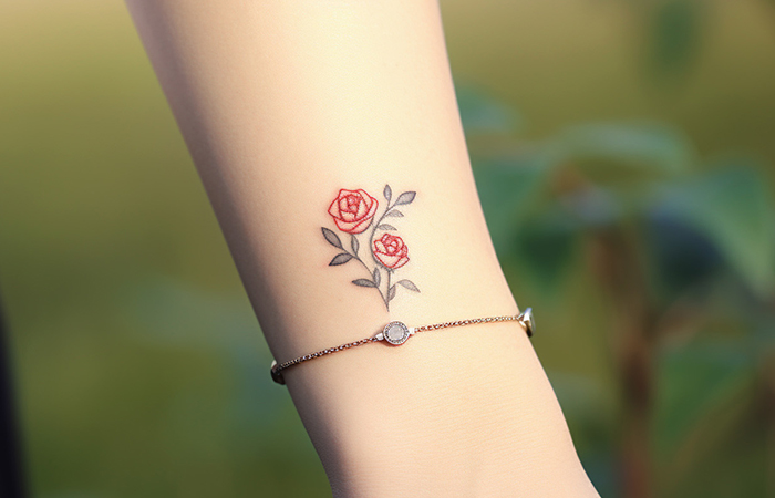 A minimal red rose line art tattoo on the wrist