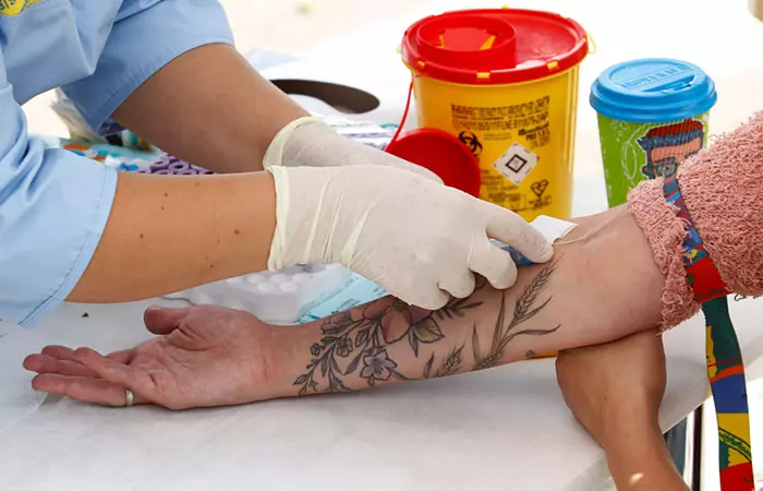 Woman with a tattoo getting her blood sugar levels tested