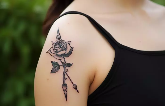 A shoulder black rose and dagger tattoo