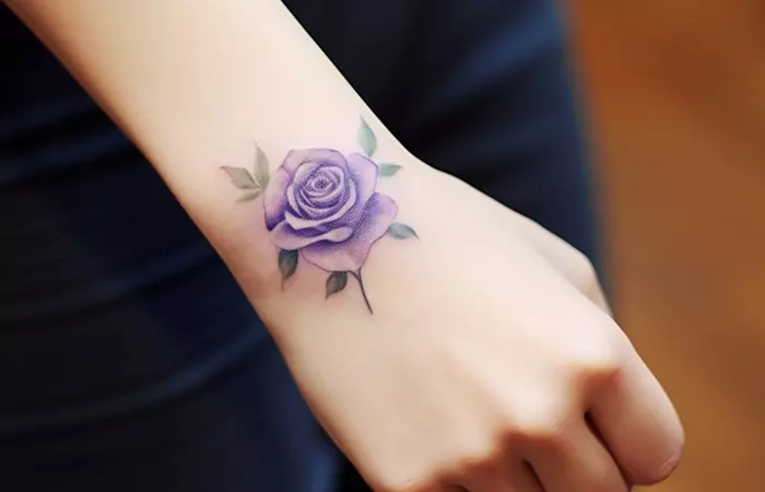 Small purple rose tattoo on the outer wrist