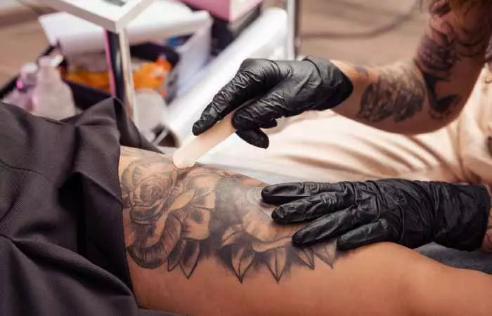 Tattoo artist applying healing cream on the tattooed skin