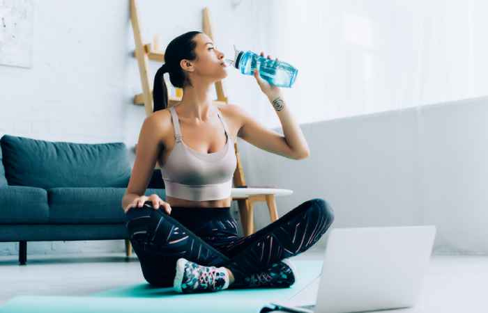 Tattooed woman taking a break after her at home workout session