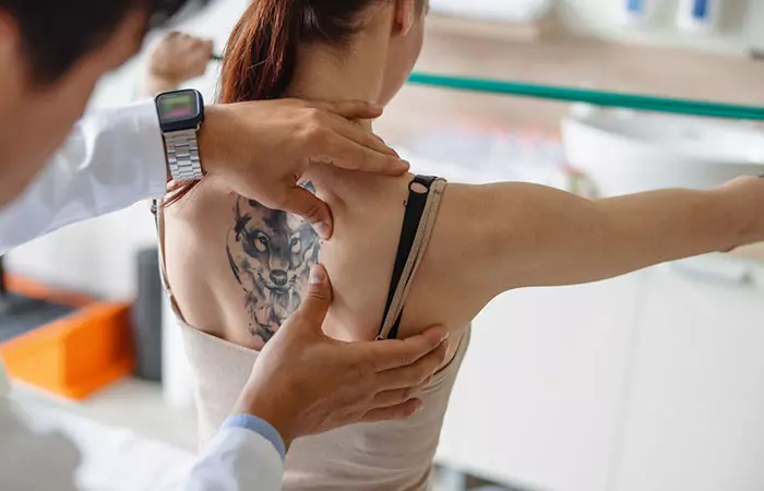 Doctor examining a tattoo on a woman’s back