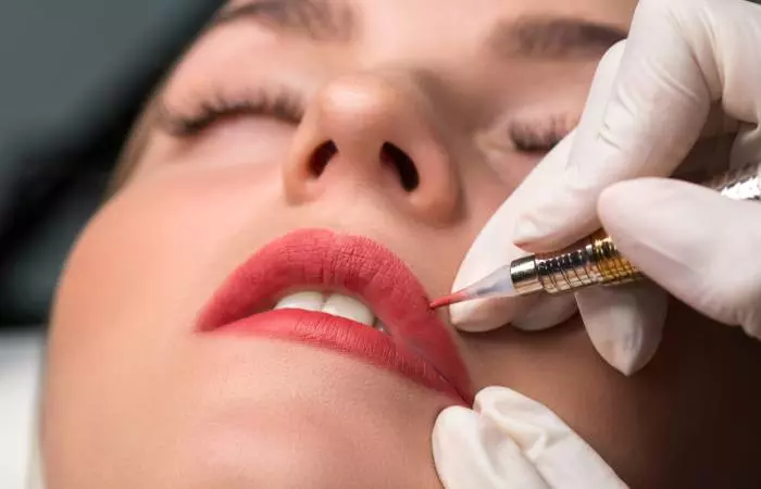 A woman receiving a permanent lip tattoo at a salon.