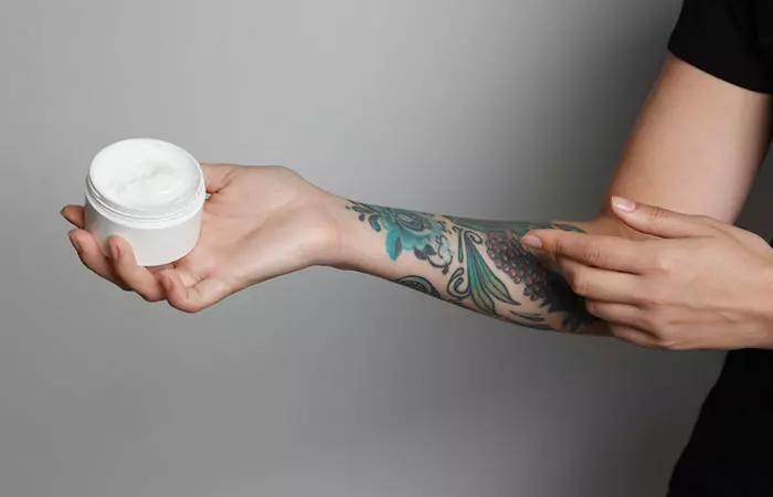 Women applying numbing cream on her arm tattoo.