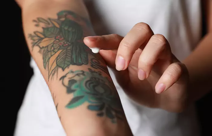 Woman applying cream on her tattoo