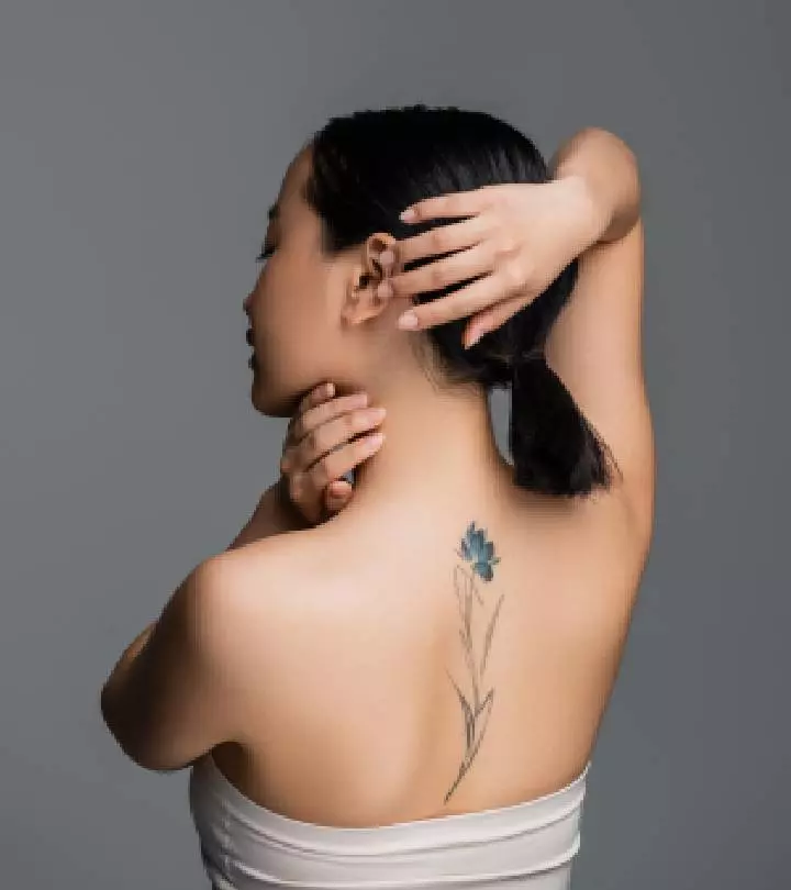 A black floral tattoo on the back of a young woman.