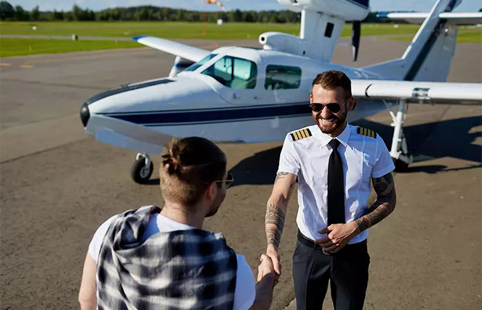 A commercial pilot with tattoos welcoming the passenger