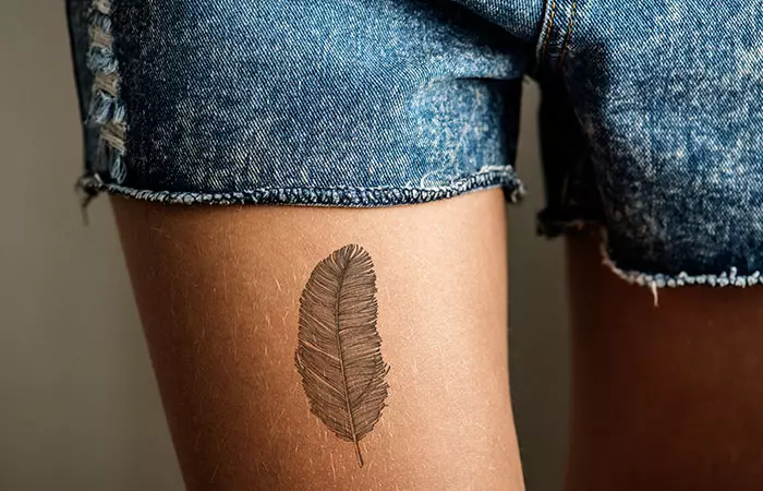 A feather tattoo on the thigh
