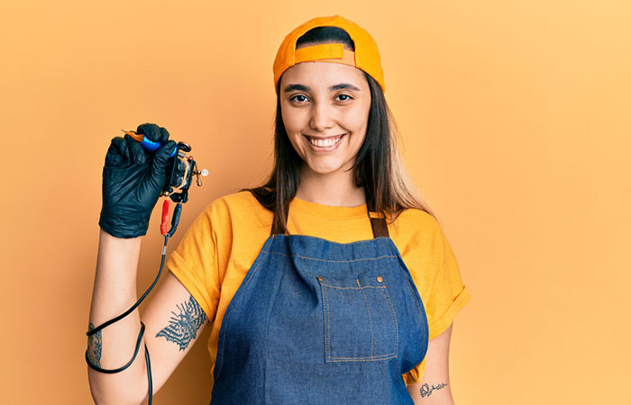 A female tattoo artist holding a tattoo machine