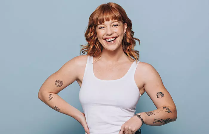 A happy woman with dainty tattoos on her arms