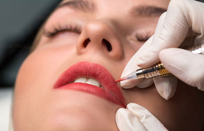 A lip tattoo artist working on a woman’s lips 