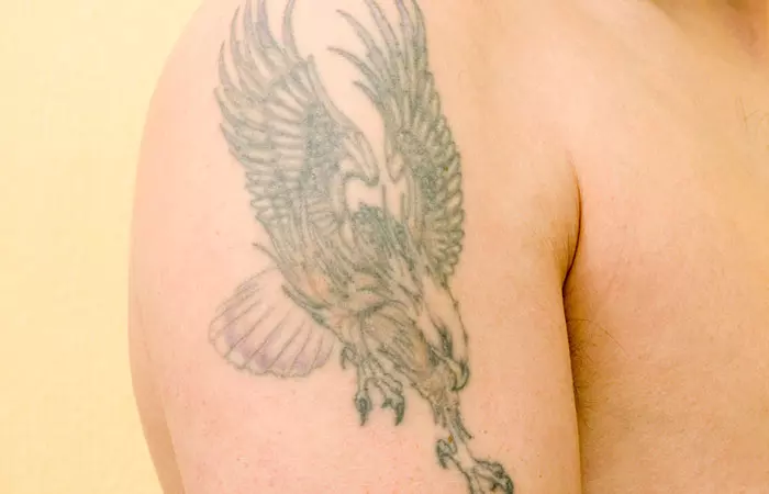 A man with a fading green bird tattoo on his shoulder