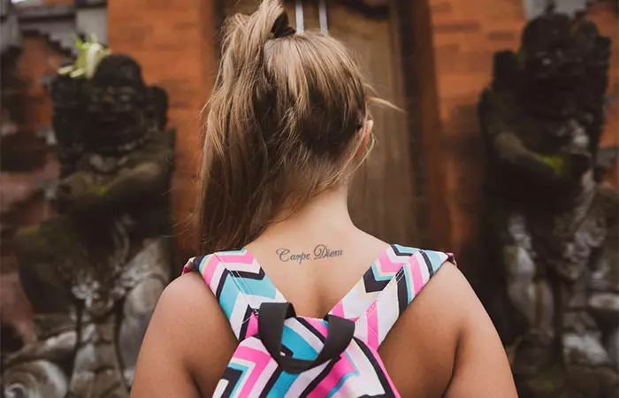 A medium size tattoo of the words “Carpe Diem” at the back of a woman