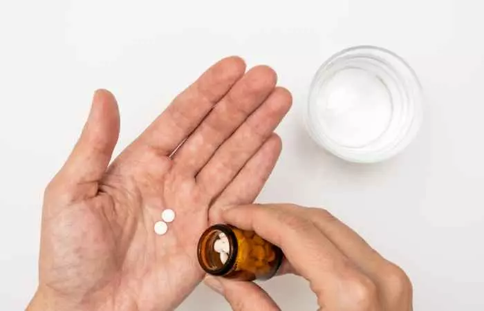A person taking blood-thinning pills from a bottle