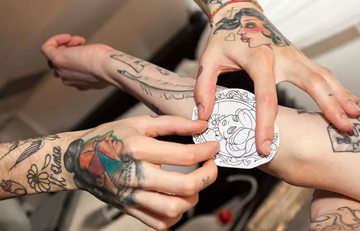 A tattoo artist applying a stencil to figure out the placement of the tattoo