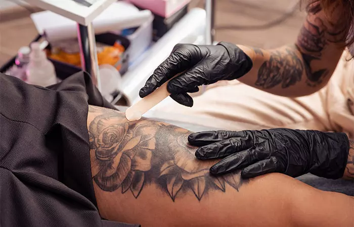 A tattoo artist applying healing cream on a fresh tattoo