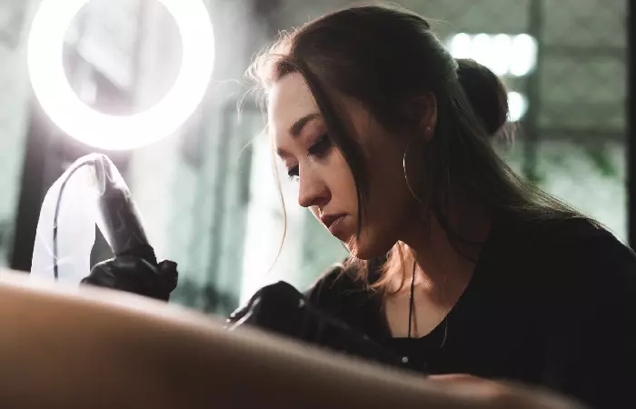 A tattoo artist inking a design on her client