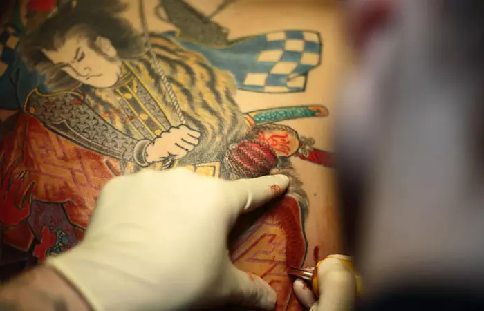 A tattoo artist making a samurai tattoo