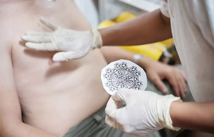 A tattoo artist using a stencil with a design selected by a client