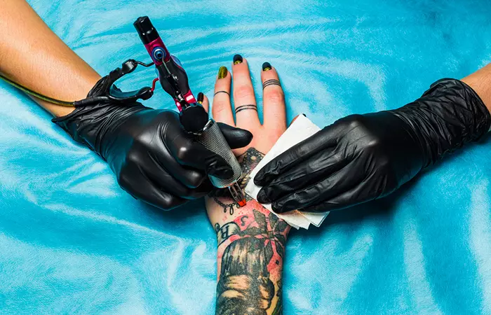 A tattoo artist working on a heavily tattooed hand
