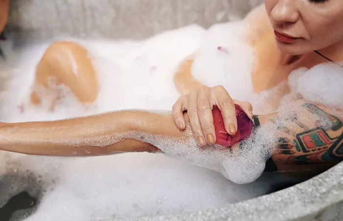 A tattooed woman cleaning her skin with soap and lukewarm water