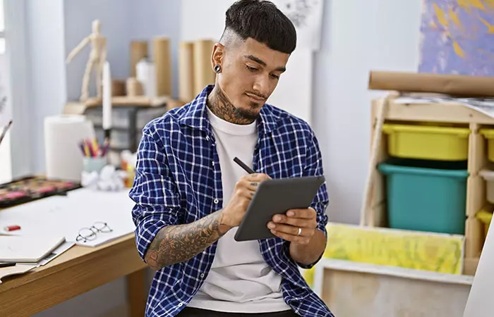 A teacher with tattoos on his forearm using a tablet for work