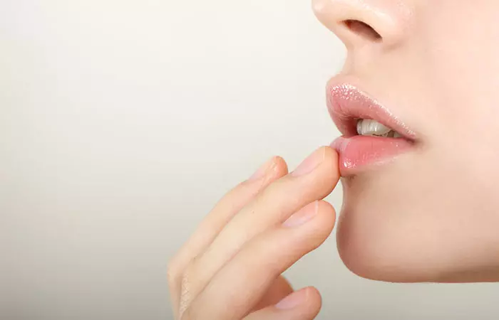 A woman applying an anti-fading cream to her lips
