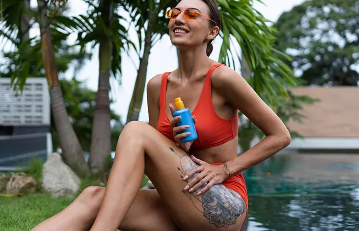 A woman applying sunscreen to her healed thigh tattoo