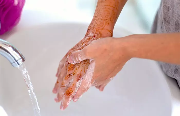 A woman vigorously washing her henna tattoo